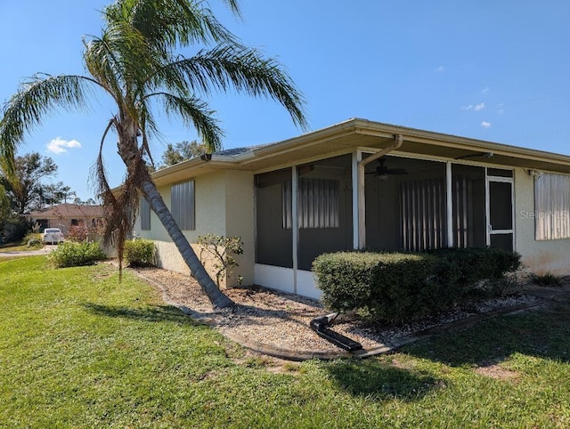 view of side of property with a lawn and ceiling fan