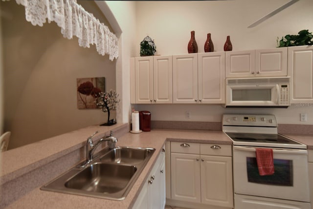 kitchen featuring sink, white cabinets, kitchen peninsula, and white appliances