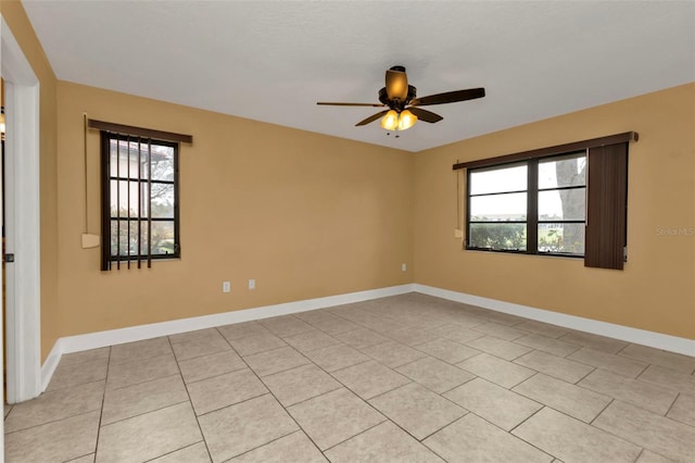 spare room with ceiling fan, light tile patterned floors, and a wealth of natural light