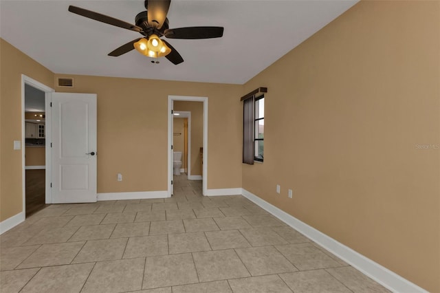 interior space with ensuite bathroom, light tile patterned floors, and ceiling fan