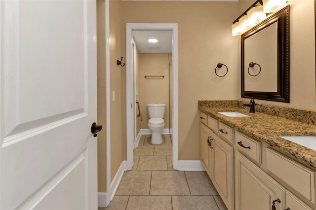 bathroom with toilet, vanity, and tile patterned floors