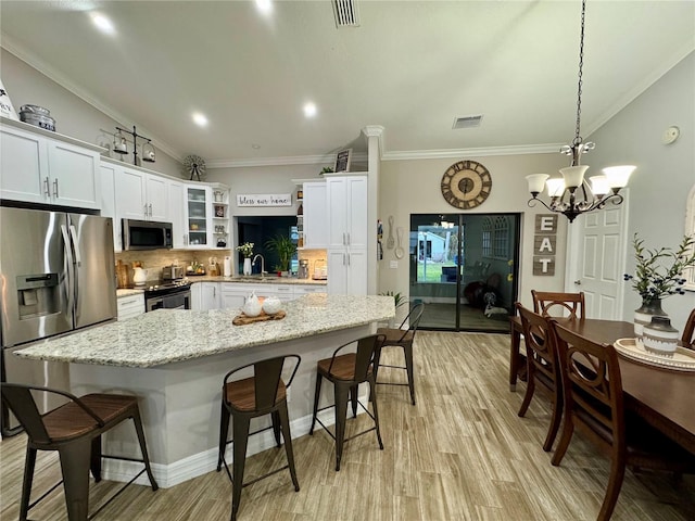 kitchen with white cabinetry, appliances with stainless steel finishes, an inviting chandelier, and pendant lighting