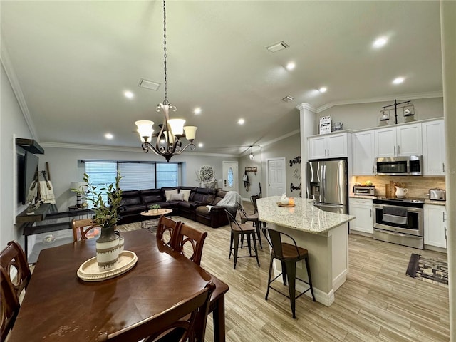 dining room featuring an inviting chandelier, ornamental molding, and light hardwood / wood-style floors