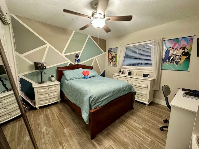 bedroom with a textured ceiling, wood-type flooring, and ceiling fan