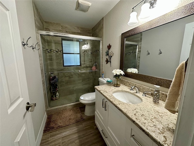 bathroom featuring toilet, walk in shower, hardwood / wood-style flooring, and vanity