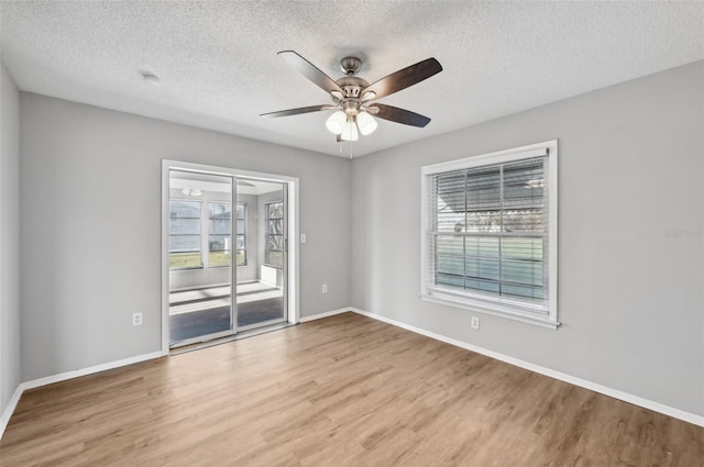 empty room with hardwood / wood-style floors, ceiling fan, a textured ceiling, and a wealth of natural light