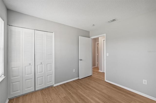 unfurnished bedroom with a closet, a textured ceiling, and light wood-type flooring