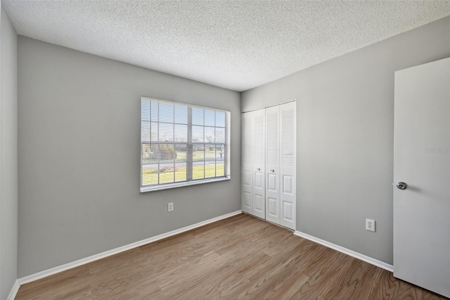 unfurnished bedroom featuring light hardwood / wood-style floors, a textured ceiling, and a closet