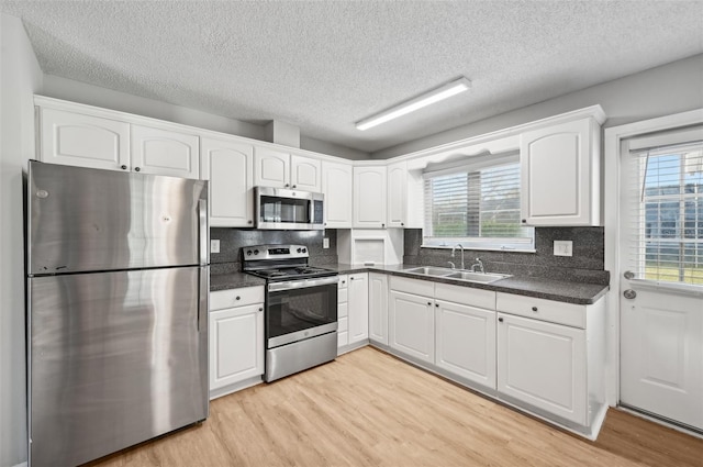 kitchen featuring white cabinets, appliances with stainless steel finishes, light hardwood / wood-style floors, and sink