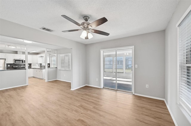 unfurnished living room with ceiling fan, light hardwood / wood-style flooring, and a textured ceiling