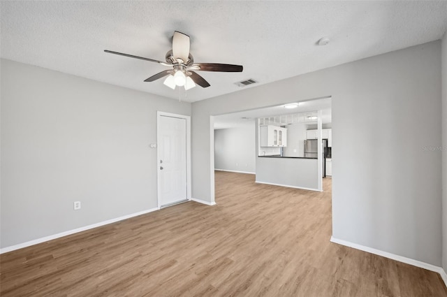 unfurnished living room featuring a textured ceiling, light wood-type flooring, and ceiling fan