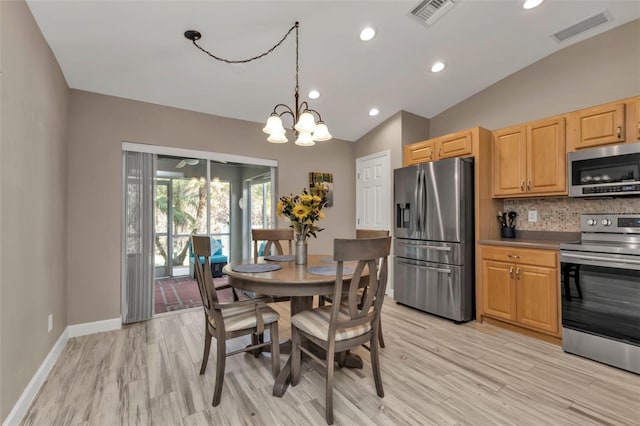 dining space featuring light hardwood / wood-style floors, a notable chandelier, and vaulted ceiling