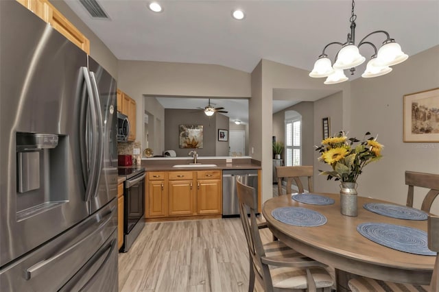 kitchen featuring hanging light fixtures, light wood-type flooring, sink, ceiling fan with notable chandelier, and stainless steel appliances