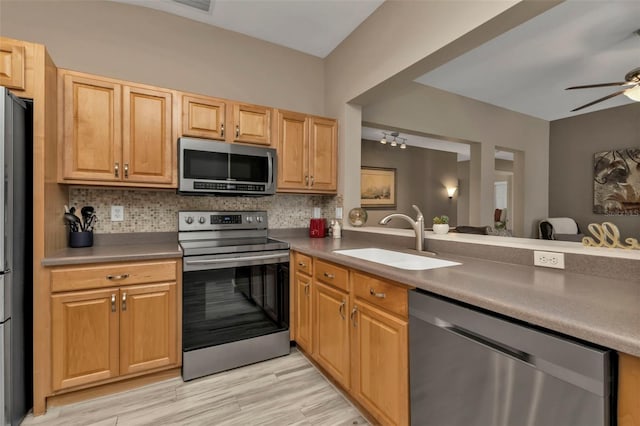 kitchen with decorative backsplash, ceiling fan, light hardwood / wood-style flooring, sink, and stainless steel appliances