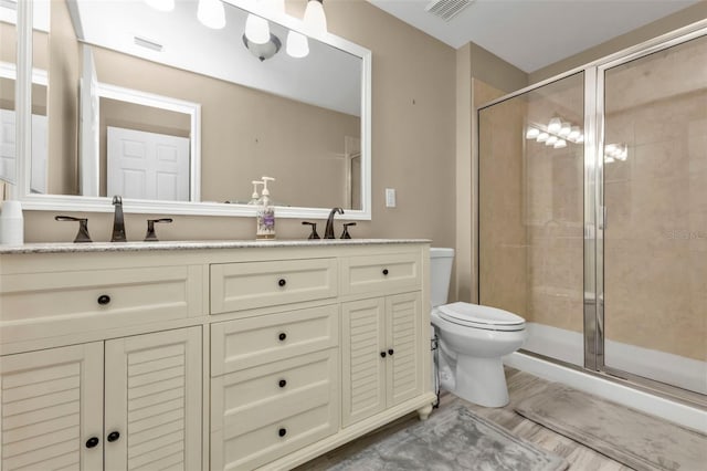 bathroom featuring toilet, vanity, and a shower with door