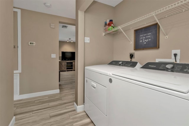 laundry room featuring light hardwood / wood-style floors and washing machine and dryer