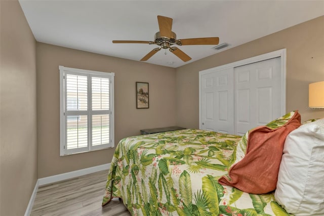 bedroom with a closet, light hardwood / wood-style floors, and ceiling fan