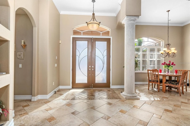 entrance foyer featuring crown molding, french doors, a chandelier, and ornate columns