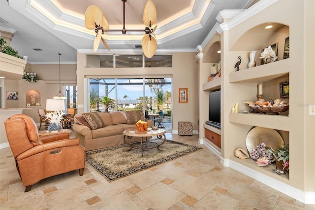 living room with a raised ceiling, ornamental molding, a high ceiling, and built in shelves