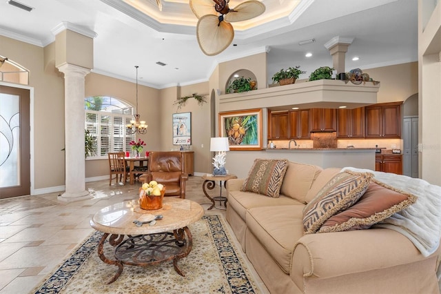 living room with ornate columns, crown molding, and ceiling fan with notable chandelier