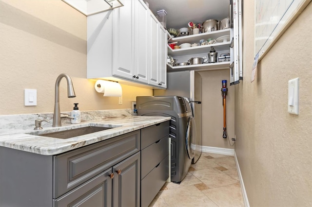 laundry room featuring light tile patterned flooring, cabinets, sink, and washing machine and clothes dryer