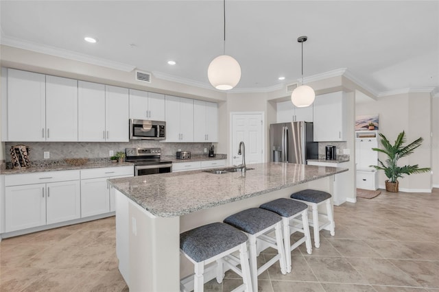 kitchen featuring white cabinets, appliances with stainless steel finishes, sink, and a kitchen island with sink