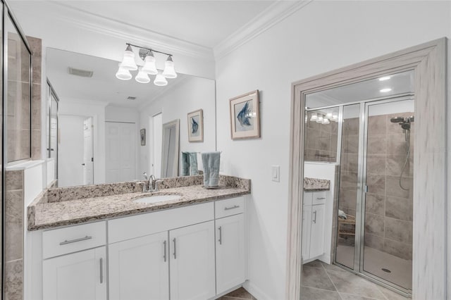 bathroom with vanity, a shower with shower door, ornamental molding, and tile patterned floors