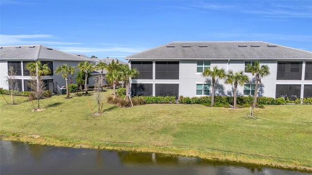 back of house with a yard and a water view