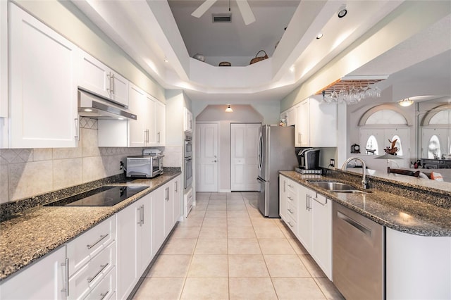 kitchen with stainless steel appliances, white cabinetry, decorative backsplash, sink, and dark stone countertops