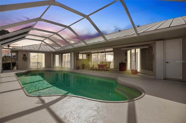 pool at dusk featuring a lanai and a patio