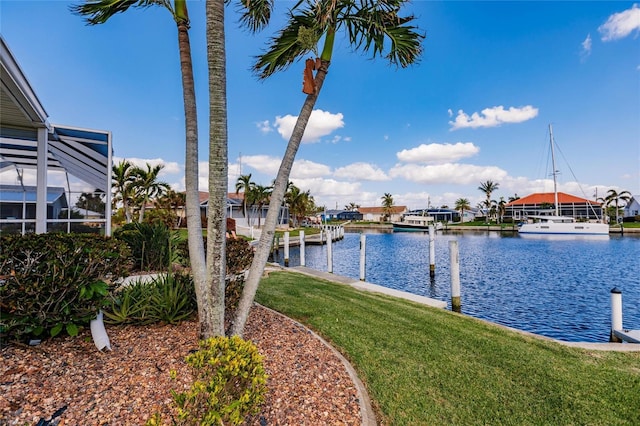 dock area featuring a water view, a lanai, and a yard