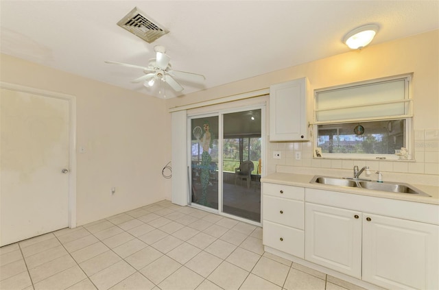 kitchen with white cabinetry, sink, ceiling fan, backsplash, and light tile patterned floors