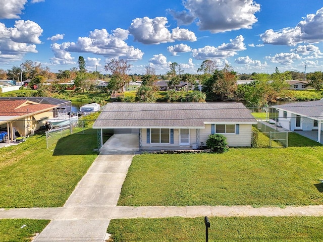 view of front of property with driveway, a residential view, an attached carport, fence, and a front lawn