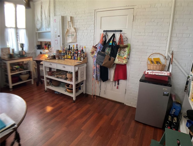 kitchen with butcher block counters, dark hardwood / wood-style floors, and brick wall