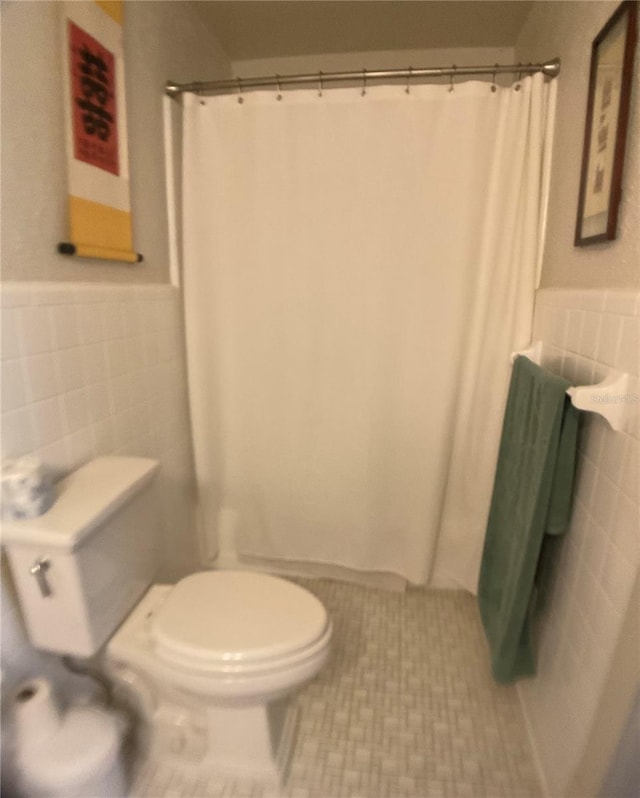 bathroom featuring toilet and tile walls