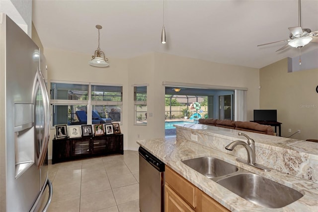 kitchen featuring sink, light stone counters, stainless steel appliances, and light tile patterned floors