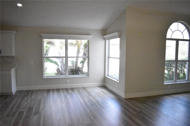 unfurnished living room featuring dark hardwood / wood-style floors and vaulted ceiling