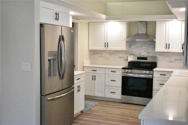 kitchen with decorative backsplash, appliances with stainless steel finishes, white cabinetry, and wall chimney range hood