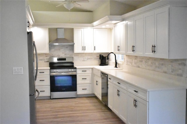 kitchen featuring sink, wall chimney range hood, backsplash, white cabinets, and appliances with stainless steel finishes