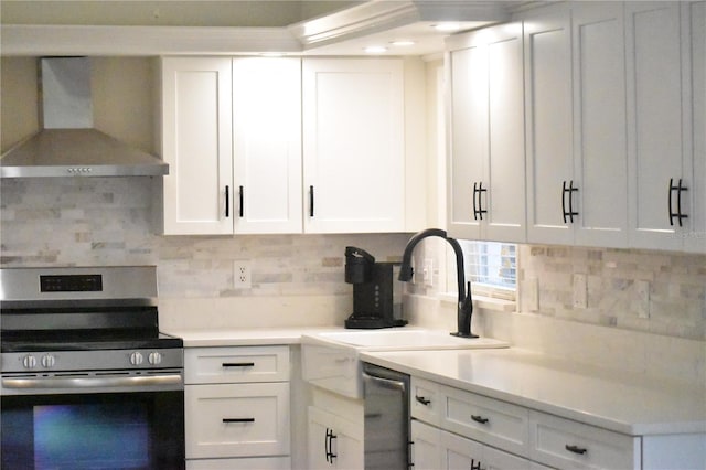 kitchen with white cabinets, wall chimney range hood, and appliances with stainless steel finishes