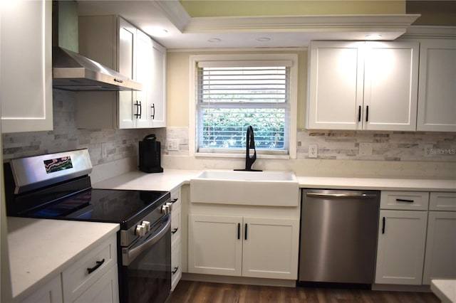 kitchen featuring sink, stainless steel appliances, wall chimney range hood, decorative backsplash, and white cabinets