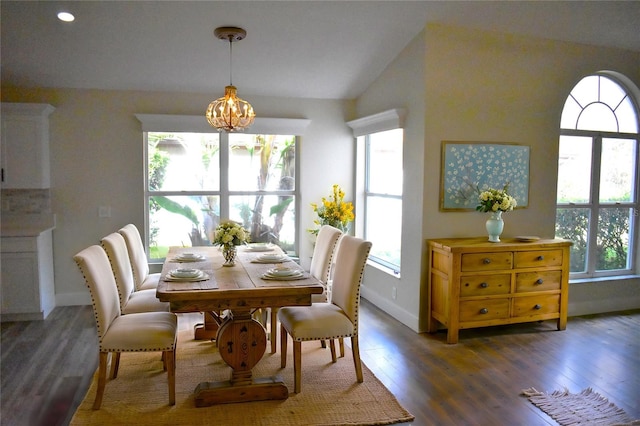 dining room with vaulted ceiling, dark hardwood / wood-style floors, and an inviting chandelier