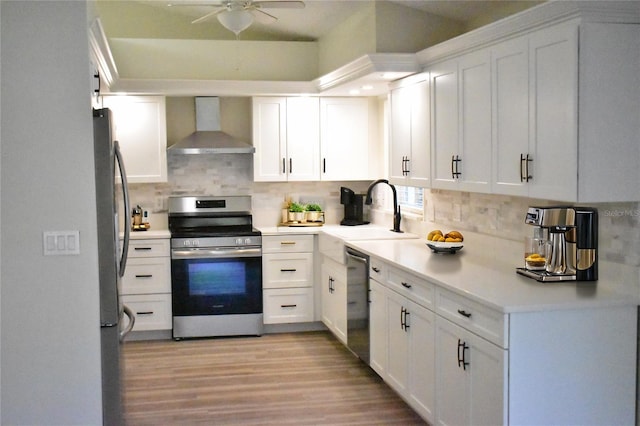 kitchen featuring wall chimney range hood, light hardwood / wood-style flooring, white cabinetry, stainless steel appliances, and decorative backsplash