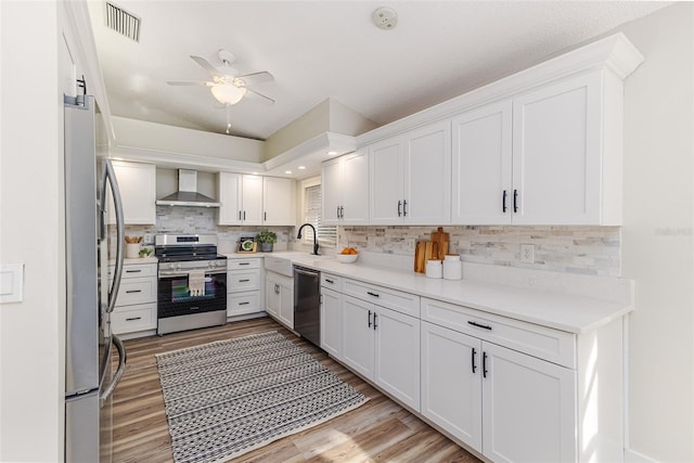 956 Harbor Town Dr, Venice, FL 34292 - kitchen featuring stainless steel appliances, wall chimney range hood, light wood-style floors, light countertops, and backsplash