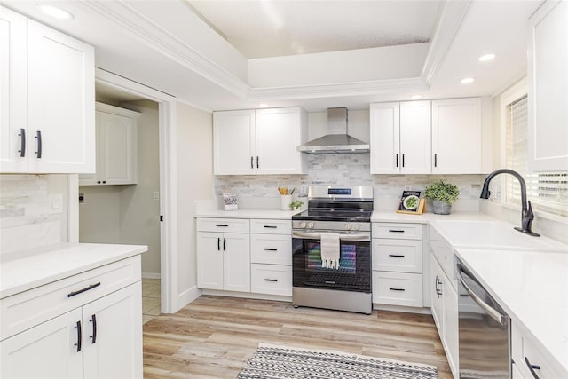 956 Harbor Town Dr, Venice, FL 34292 - kitchen with wall chimney range hood, appliances with stainless steel finishes, a sink, white cabinetry, and light wood-type flooring