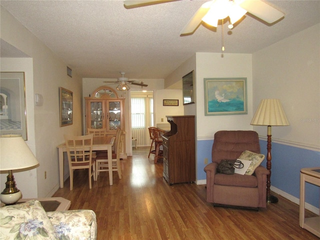 living room featuring a textured ceiling, hardwood / wood-style flooring, and ceiling fan