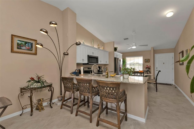 kitchen featuring vaulted ceiling, white cabinets, kitchen peninsula, and stainless steel appliances