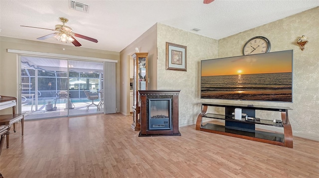 living room featuring light hardwood / wood-style floors, a textured ceiling, and ceiling fan