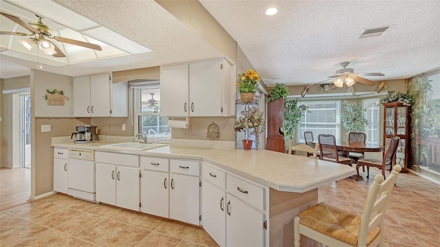 kitchen with dishwasher, kitchen peninsula, a healthy amount of sunlight, and white cabinets