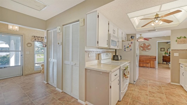 kitchen with a tray ceiling, white cabinetry, white appliances, and ceiling fan